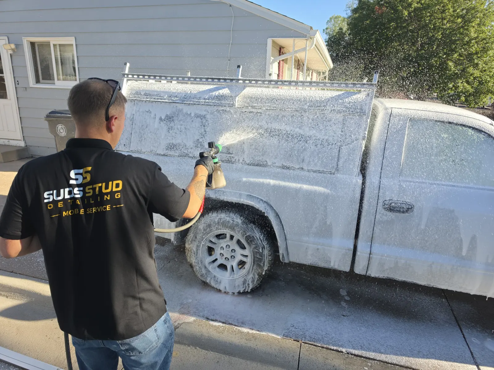 Zach washing a customer's SUV with the Suds Stud mobile setup